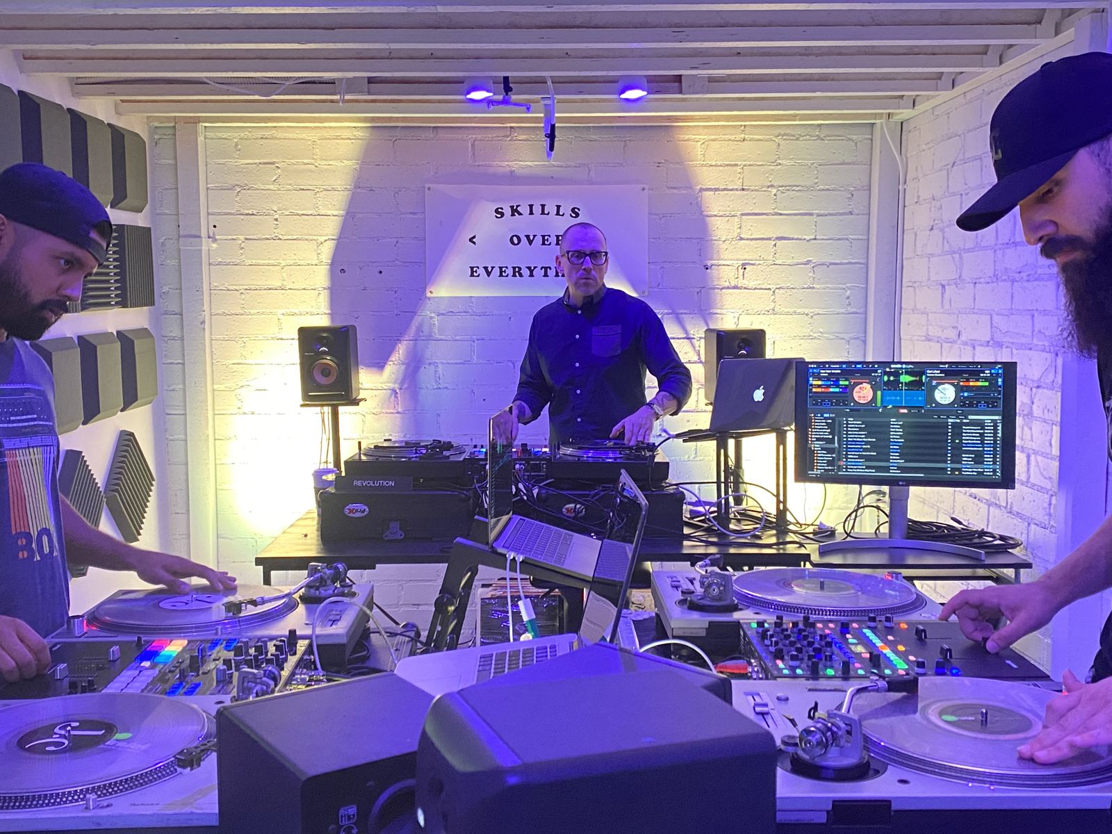 A Skills Over Everything class, students cutting on turntables under purple light